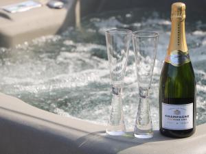a bottle of champagne and two glasses in a bath tub at Chalet 2 in Ganton +15 photos