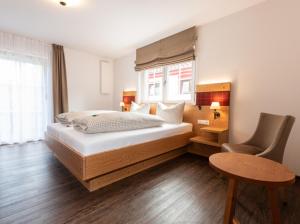 een slaapkamer met een bed, een tafel en een stoel bij Landgasthof Linde Hepbach, Hotel & Restaurant in Markdorf