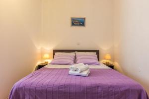 a bedroom with a purple bed with two towels on it at Mila apartments in old town centre in Zadar