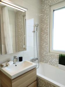 a bathroom with a sink and a tub and a mirror at NEST2 Apartments in Keszthely