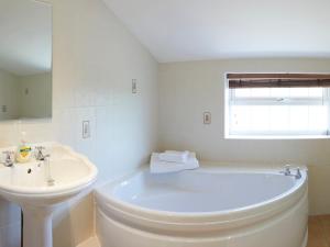 a white bathroom with a tub and a sink at Courtyard Cottage in Filey +11 photos