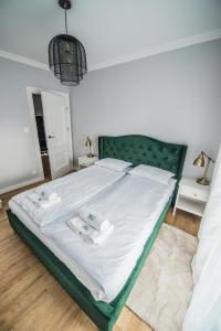 a bedroom with a bed with white sheets and a green headboard at Słone Residence Apartamenty & Beer SPA in Kudowa-Zdrój