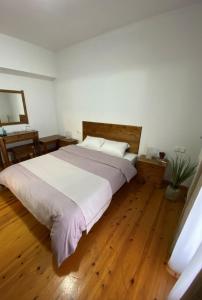 sypialnia z dużym łóżkiem i drewnianą podłogą w obiekcie Ξενώνας Ράπτης 