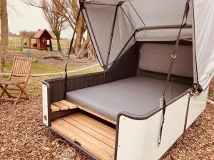 ein Bett in einem Zelt mit einem Stuhl auf einem Feld in der Unterkunft Hof Steinhütten Schlafstrandkorb in Westerhever