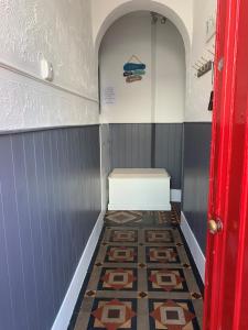 a small bathroom with a tile floor and a red door at BERNARDS HIDEOUT in Cromer