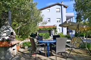 a blue table and chairs in a yard with a white house at apartmani Novotny- žuti in Rab