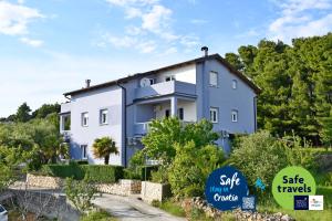 a blue and white house with signs in front of it at apartmani Novotny- žuti in Rab +4 photos