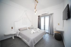 a white bedroom with a bed and a sink at Eunoia Apartments in Fira