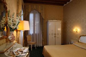 ein Hotelzimmer mit einem Bett und einer Vase aus Blumen in der Unterkunft Locanda Correr in Venedig