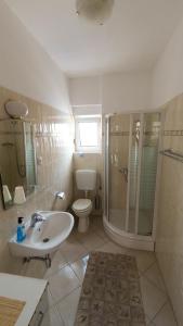 La salle de bains est pourvue de toilettes, d'un lavabo et d'une douche. dans l'établissement Apartments Juraga, à Murter