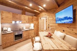 a kitchen and dining room with a wooden wall at iFlat Chalet Carole Ortisei in Ortisei