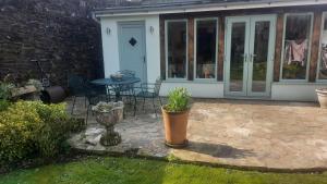 a patio with a table and chairs and a door at 2 Mill Cottages in Cornworthy