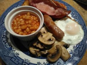 um prato azul e branco de alimentos com ovos, feijão e bacon em 2 Mill Cottages em Cornworthy