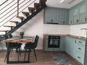 a kitchen with green cabinets and a table with chairs at Cozy loft apartament in Sighetu Marmaţiei