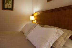 um quarto com uma cama com almofadas brancas em Hotel Lusitano em Vilar Formoso
