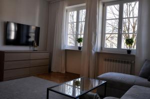 a living room with a couch and a tv and two windows at Best Rest Warszawa Stare Miasto in Warsaw