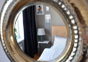 a mirror reflecting a bedroom with a bed and a lamp at Best Rest Warszawa Stare Miasto in Warsaw
