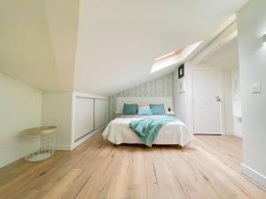 biała sypialnia z łóżkiem i drewnianą podłogą w obiekcie Apartamento Milo Ordoño w mieście León