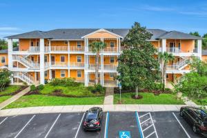 un edificio de apartamentos con coches aparcados en un aparcamiento en Bahama Bay Resort 18702, en Kissimmee