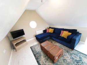 a living room with a blue couch and a suitcase at Beautiful 2 bedroom guest house with private pool in Lacock, Wiltshire in Lacock
