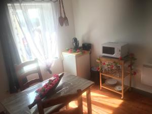 a living room with a table and a microwave at Logement détente avec jacuzzi et billard américain in Fournols