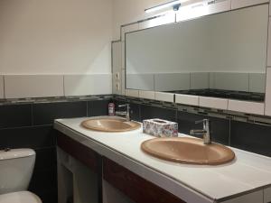 bagno con 2 lavandini, specchio e servizi igienici di Logement détente avec jacuzzi et billard américain a Fournols