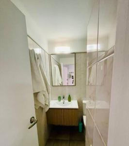 uma casa de banho com um lavatório, um espelho e um chuveiro em Departamento mall costanera em Santiago