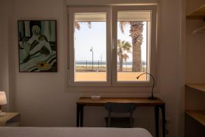 Schlafzimmer mit einem Schreibtisch und einem Fenster mit Blick auf den Strand in der Unterkunft Apartamento en primera línea de playa in Tarifa