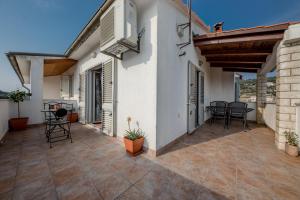 eine Terrasse eines Hauses mit Stühlen und einem Tisch in der Unterkunft Nikolina Rab Apartments in Rab