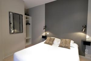 a bedroom with a white bed with two pillows on it at France Hôtel in Niort