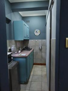 a kitchen with blue cabinets and a tile floor at Ebenezer Self Catering in Groblersdal