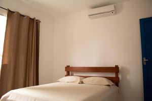 a bedroom with a bed with white sheets and a window at Solar Vila Mirim in Praia Grande