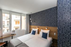 a bedroom with a white bed with blue pillows at Roombach Hotel Budapest Center in Budapest