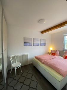 ein Schlafzimmer mit einem rosa Bett und einem Stuhl in der Unterkunft Ferienhaus Nordstrand in Horumersiel