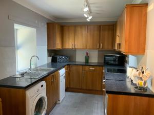 a kitchen with wooden cabinets and a washer and dryer at Charming Parlour Cottage at Tinto Retreats near Biggar in Wiston