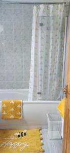 a bath tub with a shower curtain and a yellow rug at Charming Parlour Cottage at Tinto Retreats near Biggar in Wiston