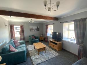 sala de estar con sofá azul y TV en Charming Parlour Cottage at Tinto Retreats near Biggar en Wiston