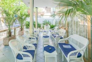 um pátio com mesas e cadeiras brancas e palmeiras em Hotel Pamela em Rimini