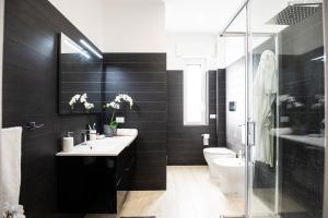 a black bathroom with a sink and a toilet at CDO Apartment in Capo dʼOrlando