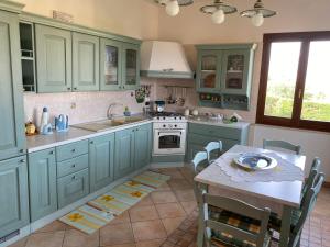 eine Küche mit grünen Schränken und einem Tisch mit einem Teller darauf in der Unterkunft Villa dei Tramonti in Custonaci