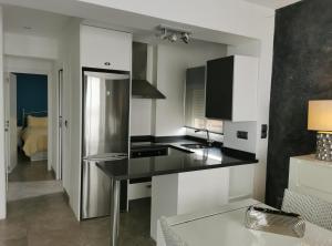 a kitchen with white cabinets and a black counter top at Beach front Esther 4 villajoyosa in Villajoyosa