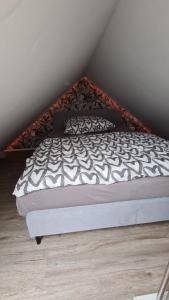 a bed with a black and white comforter in a bedroom at Tiny House Südliches Friesland-FRI Natur erleben in Bockhorn