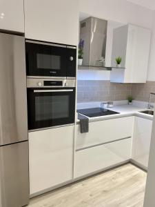 a kitchen with white cabinets and a black microwave at Bilbao Azkuna Home Centro EBI01832 in Bilbao +14 photos