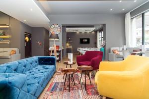 a living room with a blue couch and two yellow chairs at Roombach Hotel Budapest Center in Budapest