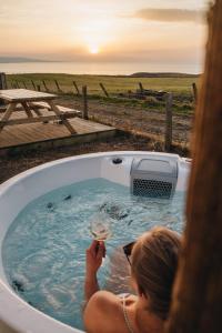 Eine Frau in einer Badewanne mit einem Glas Wein. in der Unterkunft Monkstadt Room 21 - MacQueen Cottage in Portree
