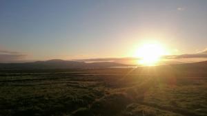 um pôr-do-sol sobre um campo com o sol no céu em Skellig View Harbour View Sunrise Apartment em Portmagee