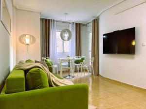 un soggiorno con divano verde e tavolo di Holiday Suite Fragata a Torrevieja