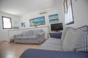 Una sala de estar con un sofá y un televisor. en Villa Maldive del Salento, en Marina di Pescoluse