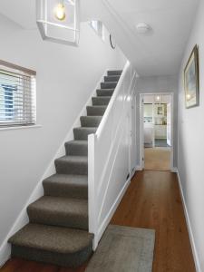 a staircase in a home with white walls and wooden floors at Sid Valley View - Scenic end of terrace town house in Sidmouth