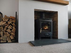 a stove in a living room with a pile of wood at Sid Valley View - Scenic end of terrace town house in Sidmouth